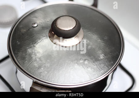 Salsa Pentola con coperchio in vetro con acqua bollente Foto Stock