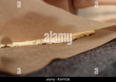 Il roll out pasta tra due fogli di carta da forno . Rendendo il sidro di mele serie a torta. Foto Stock