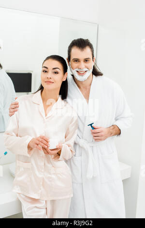 Carino coppia di accappatoi bianchi sorridente in bagno Foto Stock
