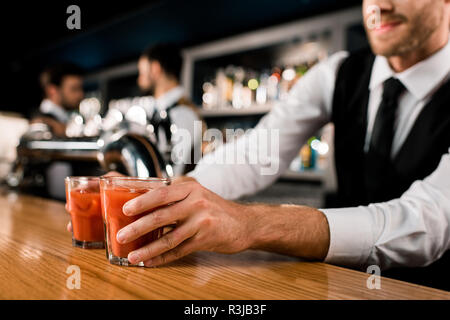 Il Barista serve bevande in bicchieri sul banco in legno Foto Stock