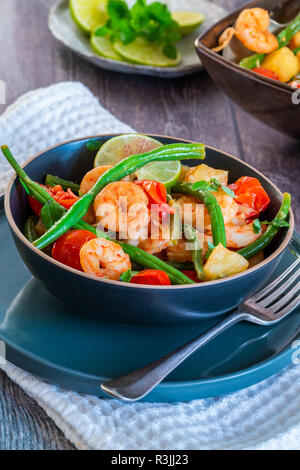 Thai di gamberi con ananas e fagioli verdi su tavola in legno rustico Foto Stock