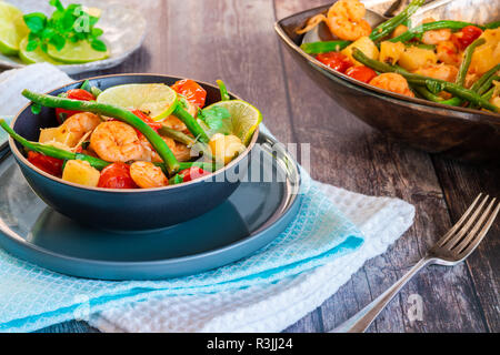 Thai di gamberi con ananas e fagioli verdi su tavola in legno rustico Foto Stock