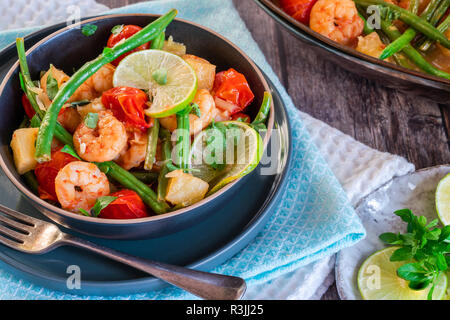 Thai di gamberi con ananas e fagioli verdi su tavola in legno rustico Foto Stock