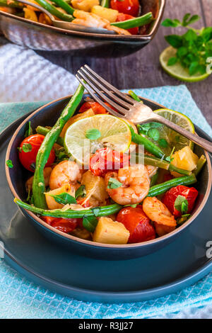 Thai di gamberi con ananas e fagioli verdi su tavola in legno rustico Foto Stock