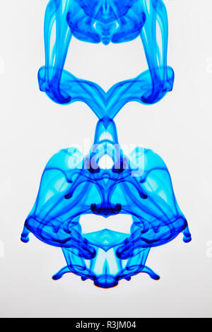 Colorante alimentare gocciolata in un bicchiere di acqua e disperdendo. Foto Stock