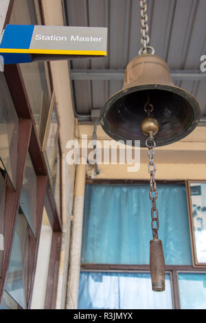 Closeup firmare la stazione master con un campanello d'oro in una stazione ferroviaria. Suono tradizionale segnalazione su piattaforma presso la stazione ferroviaria. Foto Stock