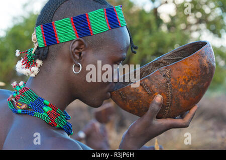 Hamar Tribe Uomo abbigliamento tradizionale di bere vino, Hamar Village, Sud Omo, Etiopia Foto Stock