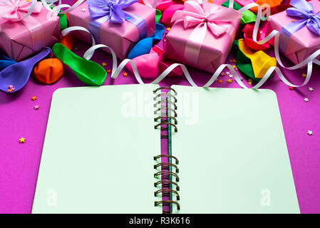 Confezione decorativa composizione con doni di raso bow palloni gonfiabili a serpentina sfondo viola. Una vista dall'alto di laici piatta Foto Stock