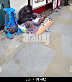 Uomo senza tetto con un cane, la lettura di un libro in The Strand, Londra, Inghilterra, Regno Unito. Foto Stock