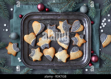 Sfondo di natale, laici piatto con biscotti natalizi in forma di cuori e stelle sul vassoio di metallo Piatto, laici sfondo scuro decorata con ramoscelli di abete, baubl Foto Stock