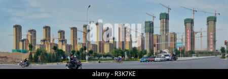 Cina, Ningxia, Yinchuan. Vista panoramica di un gruppo di alti edifici di appartamenti in varie fasi di costruzione di gru. Foto Stock