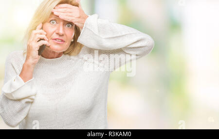 Medioevo donna bionda parlando sullo smartphone su sfondo isolato ha sottolineato con la mano sulla testa, sconvolto con vergogna e la sorpresa di fronte, arrabbiato e fru Foto Stock