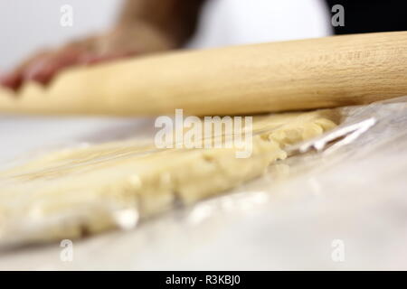 Stendere l'impasto tra due strati di pellicola trasparente. Rendendo mascarpone al limone Pie serie. Foto Stock