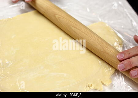 Stendere l'impasto tra due strati di pellicola trasparente. Rendendo mascarpone al limone Pie serie. Foto Stock