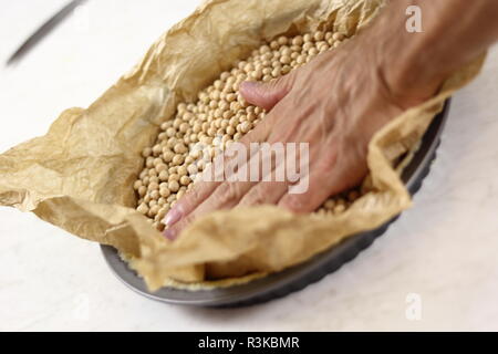 Premere e livellare la cottura i fagioli in padella. Rendendo mascarpone al limone Pie serie. Foto Stock