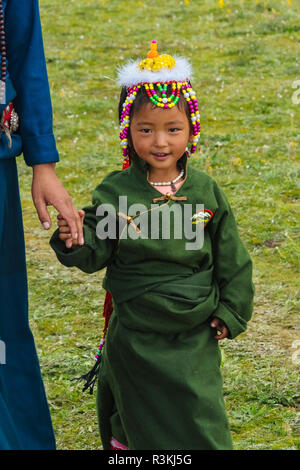 Il Tibetano Donna con bambina in abiti tradizionali a cavallo di razza Festival, Litang, western Sichuan, Cina Foto Stock