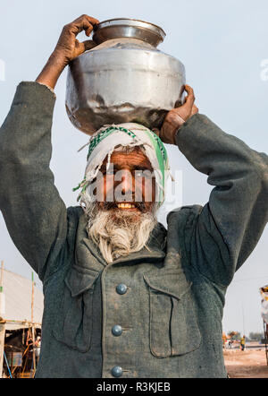 India Rajasthan. Nagaur, senza acqua né vita expedition, Nagaur fiera del bestiame, uomo che porta pentola di metallo di acqua Foto Stock