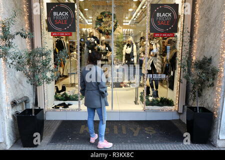 Salonicco, Grecia, Novembre 23rd, 2018. Una donna sta in piedi di fronte ad un negozio di Salonicco la via Tsimiski sul Venerdì nero. Venerdì nero shopping è stata per lungo tempo un post-tradizione del ringraziamento negli Stati Uniti, ma in Grecia è un importato di recente tradizione, e questo anno dettaglianti greci hanno esteso in "nero settimana". Credito : Orhan Tsolak / Alamy Live News Foto Stock