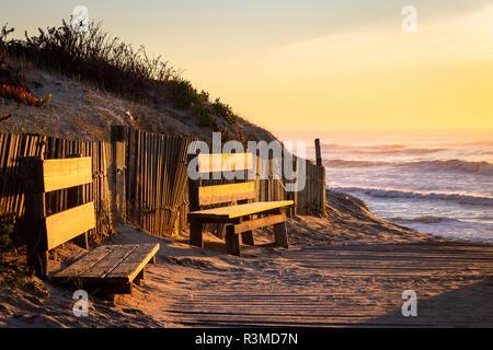 Due panche di legno in spiaggia, vicino all'oceano. Tramonto, ora d'oro, una luce calda. Copia dello spazio. Foto Stock
