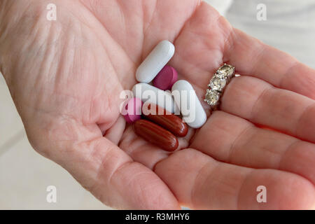 Una vista ravvicinata della mano e tenendo sette pillole e un 3 anello dimond sul lato Foto Stock