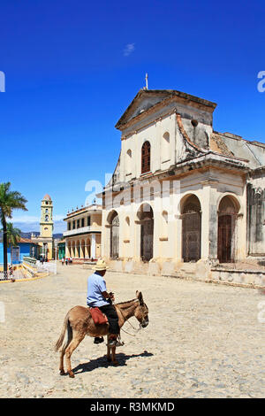 Cuba Trinidad. Un uomo su un asino gode della quiete Plaza San Francisco de Asis, chiesa, luogo sindaco, Sancti Spiritus, Foto Stock