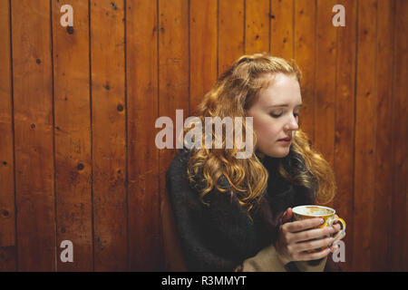 Donna che mantiene una tazza di caffè nella caffetteria Foto Stock