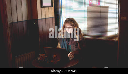 Donna che utilizza computer portatile in cafe Foto Stock