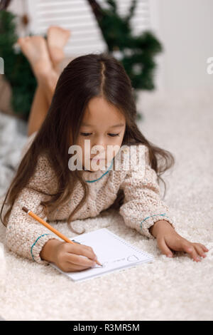 Carino bambino ragazza scrivere la lettera a Babbo Natale a casa Foto Stock