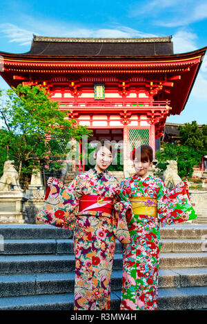 Kyoto, Giappone. Due giovani donne pongono al di fuori della porta principale di accesso al Kiyomizu-dera tempio indossando kimono, un sito Patrimonio Mondiale dell'UNESCO Foto Stock