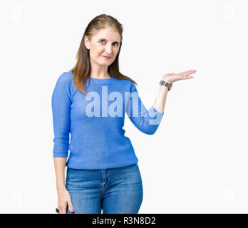 Bella la mezza età coppia donna che indossa un maglione invernale su sfondo isolato sorridente allegro presentando e dispositivo di puntamento con il palmo della mano in cerca di un Foto Stock