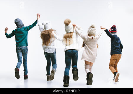 La vista posteriore del gruppo di bambini in bright abbigliamento invernale, isolato su bianco studio. Moda, infanzia felice concetto emozioni Foto Stock