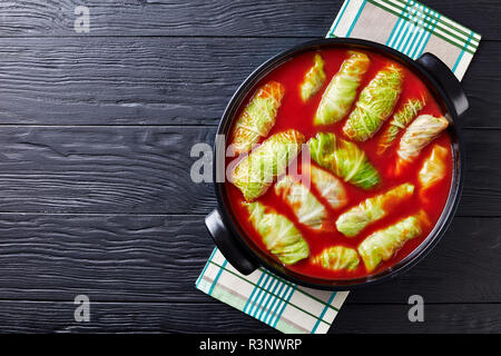 Materie foglie di cavolo ripiene di carne macinata, riso bollito preparato per cucinare con la salsa di pomodoro in forno olandese, vista da sopra, piatto laici, spazio di copia Foto Stock