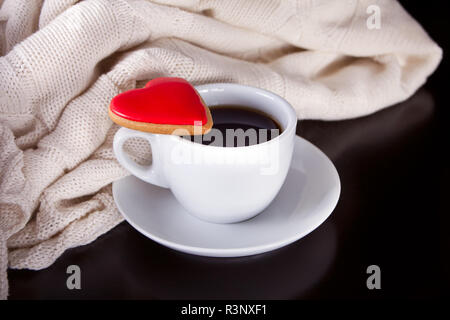 Tazza di caffè e a forma di cuore ad un cookie sul tavolo di legno Foto Stock