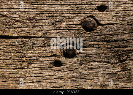 Vecchia panca di legno texture con viti in metallo, primo piano. Invecchiato in legno massiccio in stile rustico a tapparelle squallido sfondo marrone. Legno duro scuro legno stagionato superficie. Foto Stock