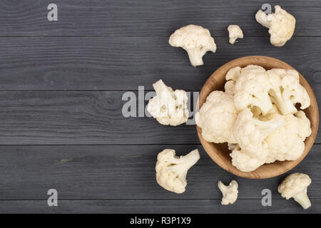 Cavolfiore fresco tagliato in piccoli pezzi di legno nero con sfondo copia dello spazio per il tuo testo. Vista dall'alto. Lay piatto Foto Stock