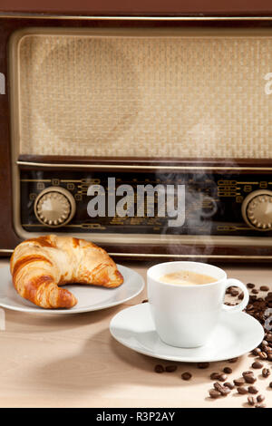 Ascolto della radio durante la prima colazione con caffè e croissant Foto Stock