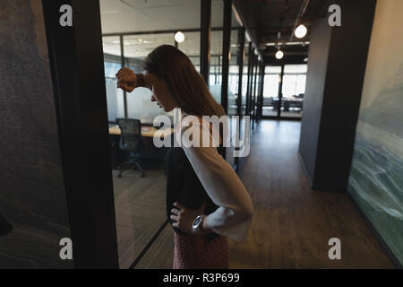 Sconvolto executive femmina in piedi in corridoio Foto Stock