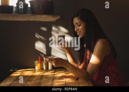 Donna che utilizza il cellulare mentre un caffè nella caffetteria Foto Stock