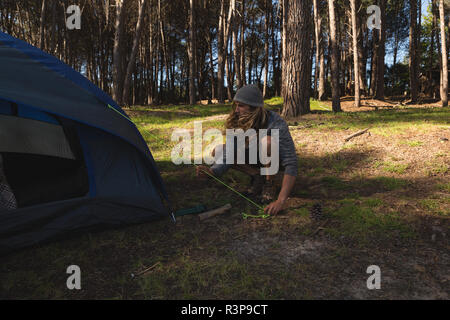 Uomo di mettere una tenda nella foresta Foto Stock