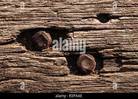 Vecchia panca di legno texture, closeup. Invecchiato in legno massiccio in stile rustico a tapparelle squallido sfondo marrone con Rusty Il dado e il bullone. Foto Stock