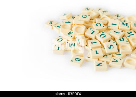 Pila di casuale gioco SCRABBLE lettera di piastrelle con valore di punteggio miscelati, isolati su sfondo bianco. Copia dello spazio. Foto Stock