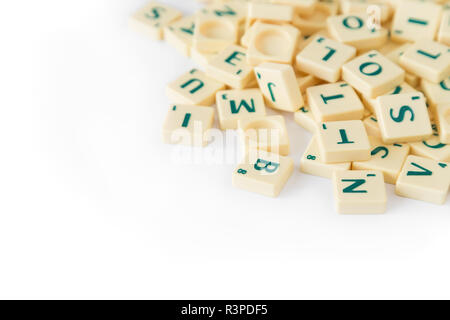 Pila di casuale gioco SCRABBLE lettera di piastrelle con valore di punteggio miscelati, isolati su sfondo bianco. Copia dello spazio. Foto Stock