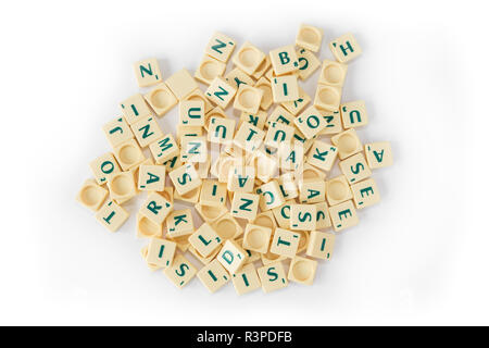 Pila di casuale gioco SCRABBLE lettera di piastrelle con valore di punteggio miscelati, visto dal di sopra, isolato su sfondo bianco. Foto Stock