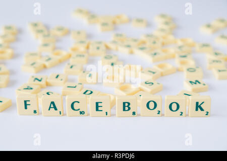 Focus sulla parola "Facebook" fatta di gioco SCRABBLE lettera di piastrelle con valore di punteggio, piastrelle casuale miscelato fino in background. Profondità di campo. Foto Stock