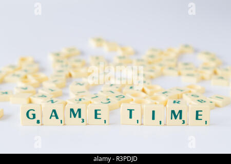 Focus sulle parole "tempo di gioco' fatto di gioco SCRABBLE lettera di piastrelle con valore di punteggio, piastrelle casuale miscelato fino in background. Profondità di campo. Foto Stock