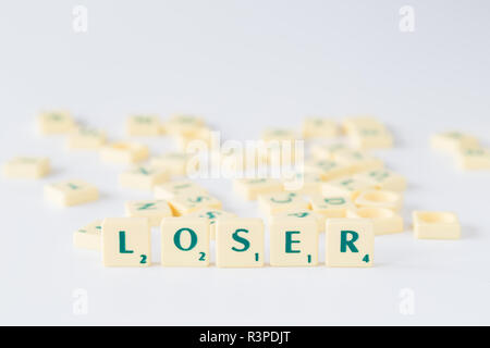 Focus sulla parola "perdente" fatta di gioco SCRABBLE lettera di piastrelle con valore di punteggio, piastrelle casuale miscelato fino in background. Profondità di campo. Foto Stock