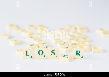 Focus sulla parola "perdente" fatta di gioco SCRABBLE lettera di piastrelle con valore di punteggio con la lettera E caduti. Piastrelle casuale miscelato fino in sfondo sfocato Foto Stock