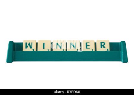 Gioco Scrabble lettera di piastrelle con valore di punteggio su un supporto formante la parola "vincitore". Isolato su sfondo bianco. Foto Stock