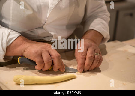 Close up di pasta making processo. La donna rende orecchiette, orecchio pasta sagomata a Eataly a Torino, Italia Foto Stock