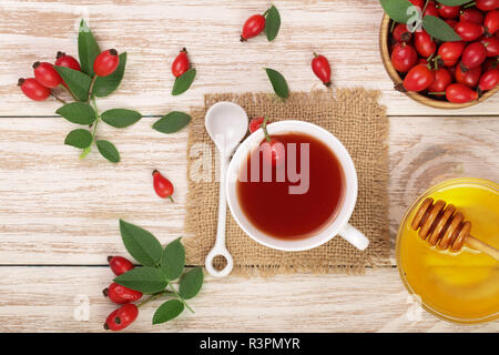 Tè con rosa canina e miele bianco su sfondo di legno. Vista superiore Foto Stock